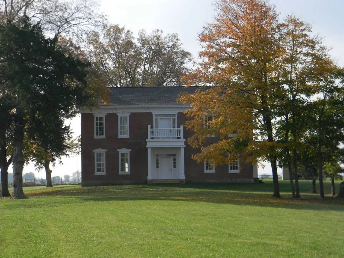 The brick farmhouse at Pharis Farm framed by autumn trees